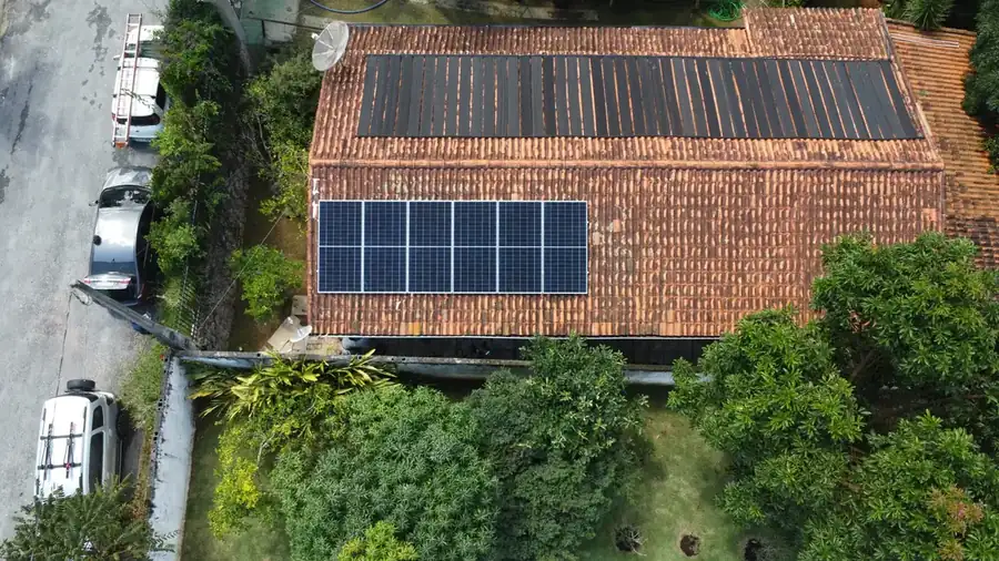 Sistema de energia solar instalado em residência cercada de árvores